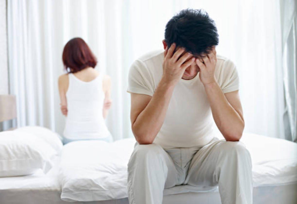 người đàn ông ôm đầu ngồi trên giường 